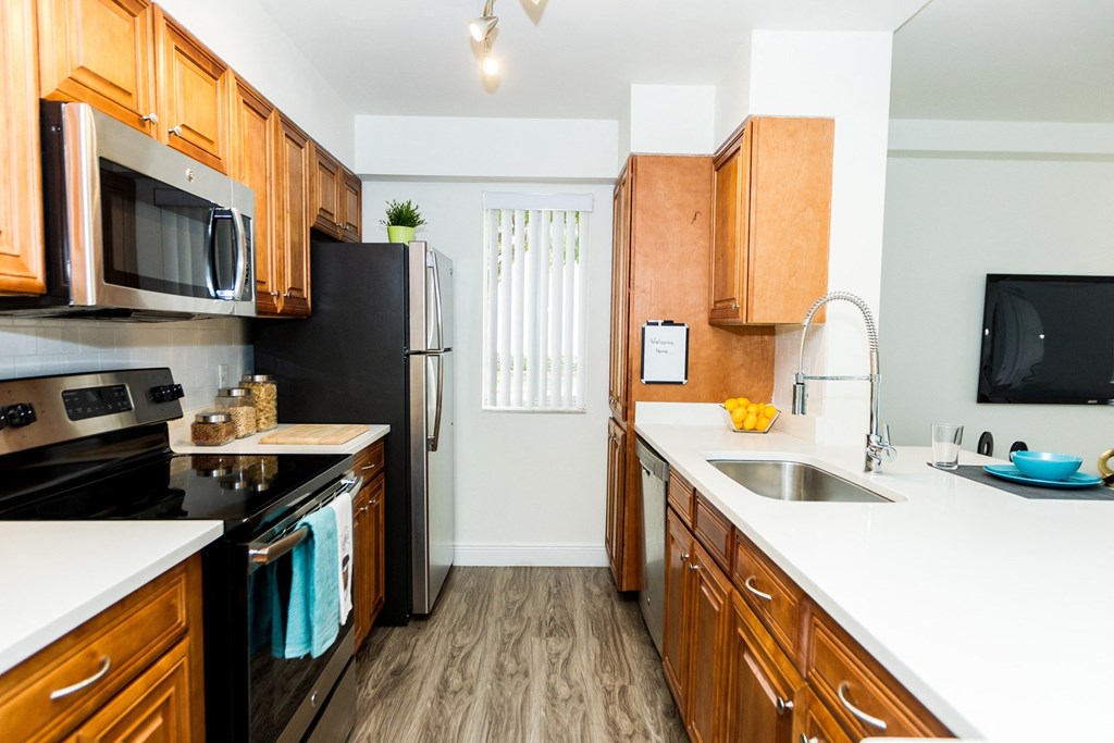 a kitchen with wooden cabinets and black appliances and white counter tops