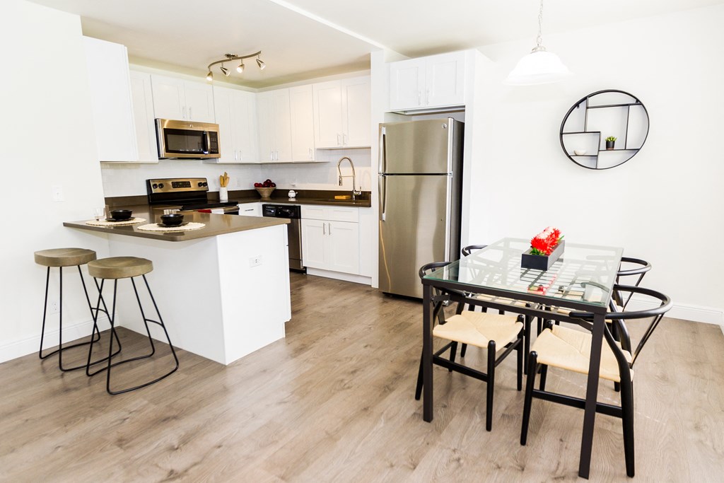 a kitchen with white cabinets and stainless steel appliances and a dining room table and chairs