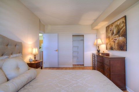 A bedroom with a large bed, a dresser, and a painting on the wall.