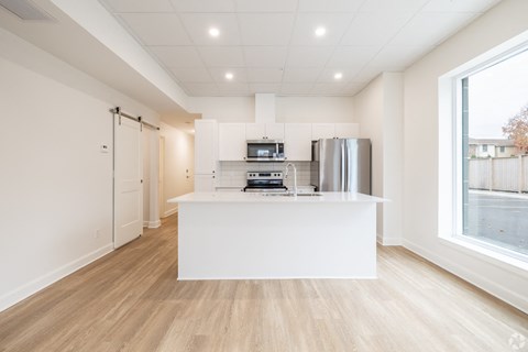 A kitchen with a white counter and wooden flooring.