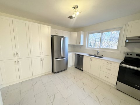 A kitchen with white cabinets and a stainless steel refrigerator.