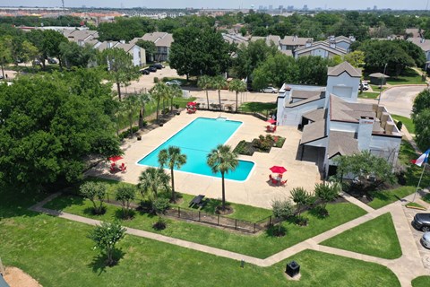 A swimming pool surrounded by a grassy area and trees.