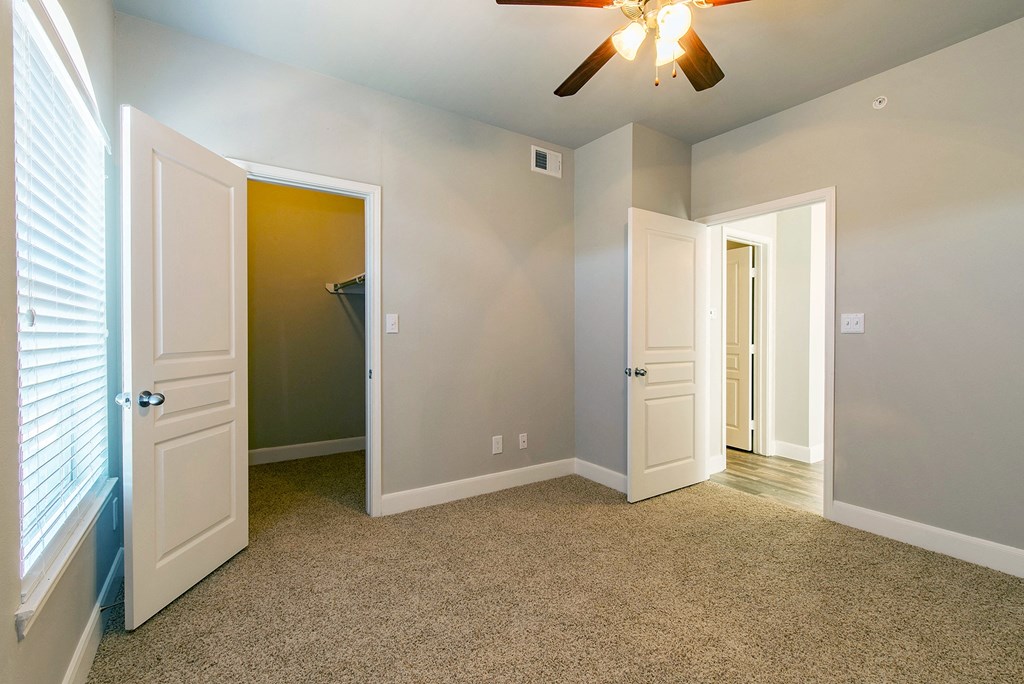 an empty room with two doors and a ceiling fan