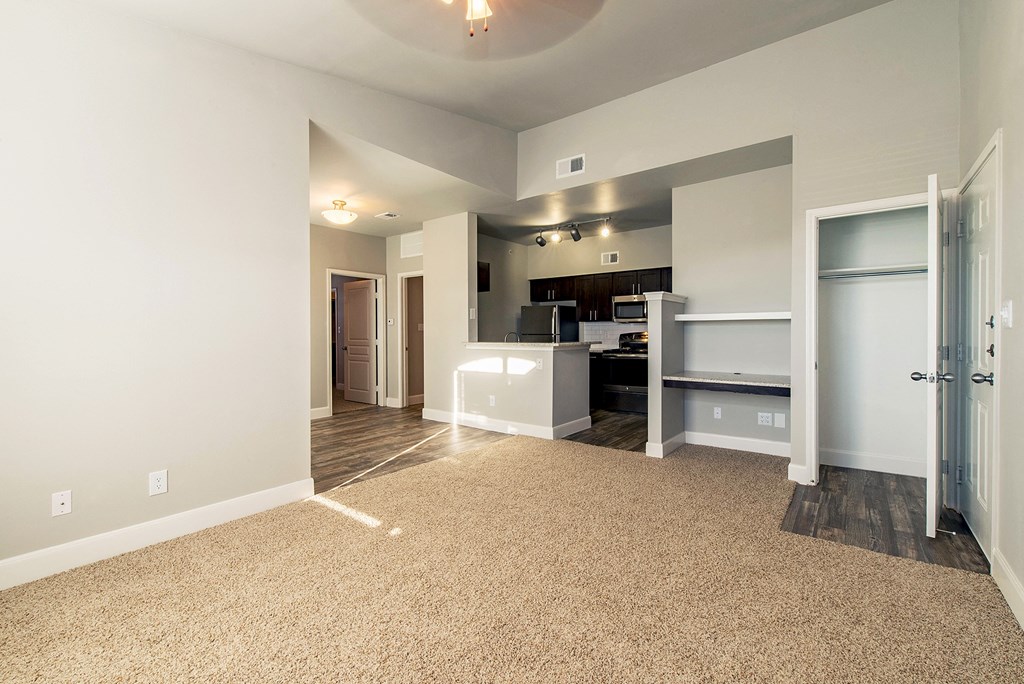 an empty living room with a door to a kitchen