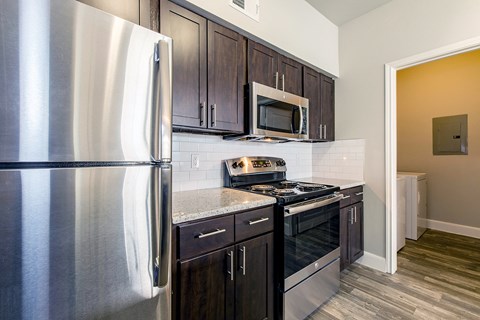 A kitchen with a stainless steel refrigerator and black cabinets.