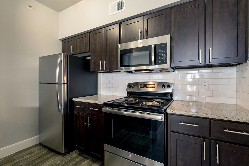 a kitchen with stainless steel appliances and dark wood cabinets