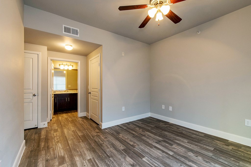 an empty living room with wood floors and a ceiling fan