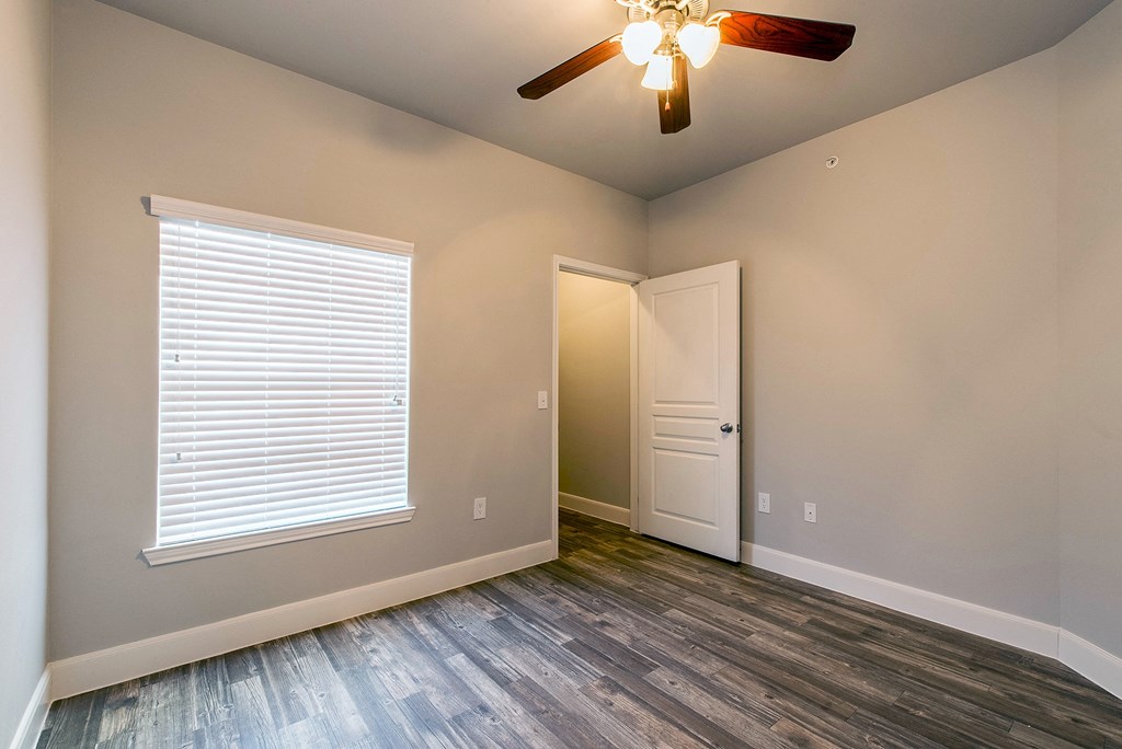 an empty bedroom with a window and a ceiling fan