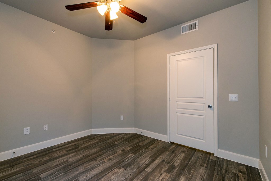 an empty room with wooden floors and a ceiling fan