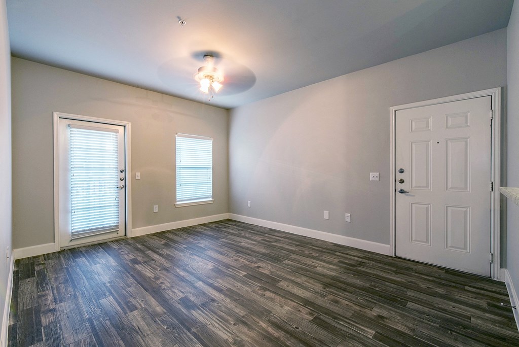 an empty living room with a white door and wood flooring