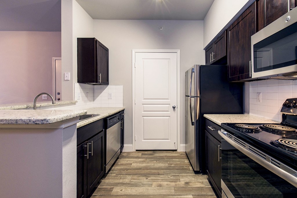 a kitchen with black appliances and white counters and a door