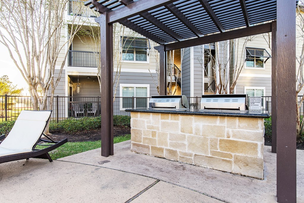 a patio with a stone bar and a chair in front of an apartment building