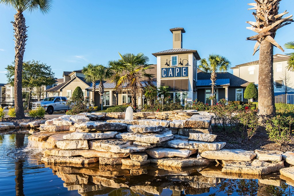 a pond in front of a building with palm trees