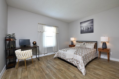 A bedroom with a bed, chair, and a painting on the wall.