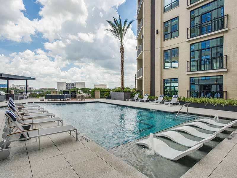 a swimming pool with chaise lounge chairs and a palm tree in the background