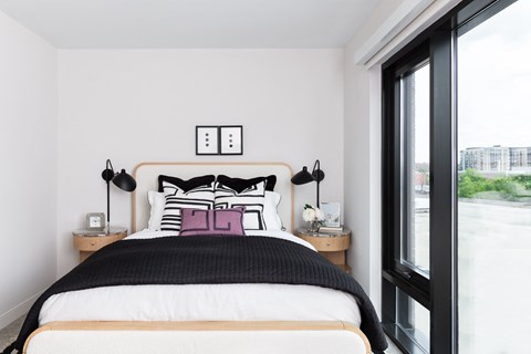 A bedroom with a large bed and a window overlooking a street.