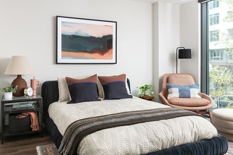 A bedroom with a large bed and a painting on the wall.