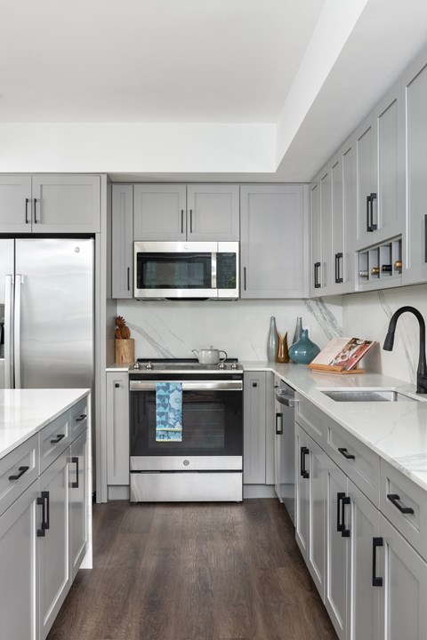 A modern kitchen with white cabinets and stainless steel appliances.