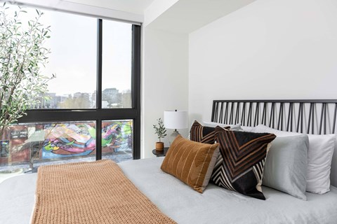 A bedroom with a large bed and a view of the city through the window.