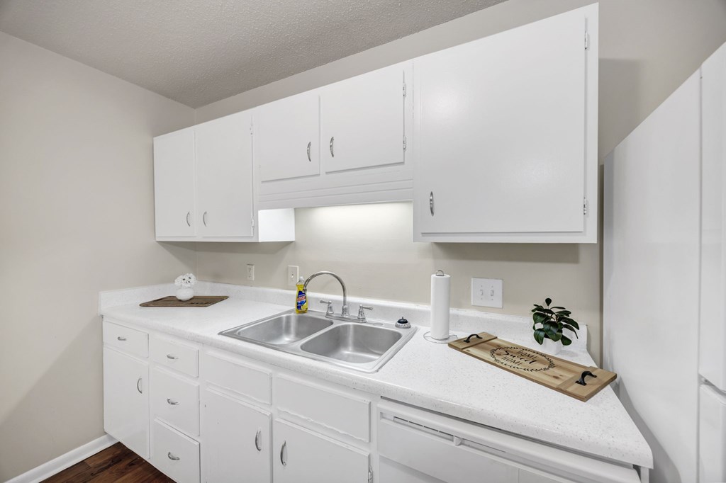 A white kitchen with a sink and cabinets at Peachtree Place Apartments, South Carolina, 29210