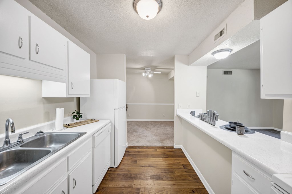 A kitchen with white cabinets and a wooden floor at Peachtree Place Apartments, Columbia, South Carolina