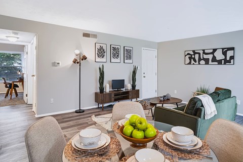 A dining room with a table set for two and a bowl of apples in the center.