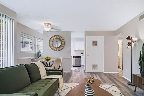 A living room with a green couch and a round mirror on the wall.