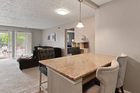 an open kitchen and living room with a granite counter top and a couch