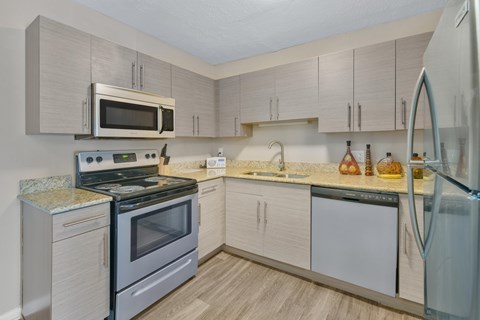A kitchen with a refrigerator, sink, and stove.
