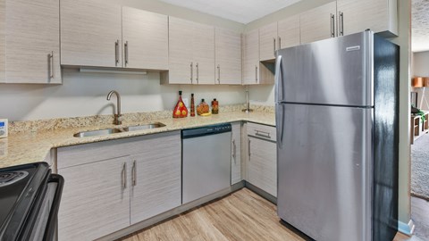 A kitchen with a stainless steel refrigerator and wooden cabinets.