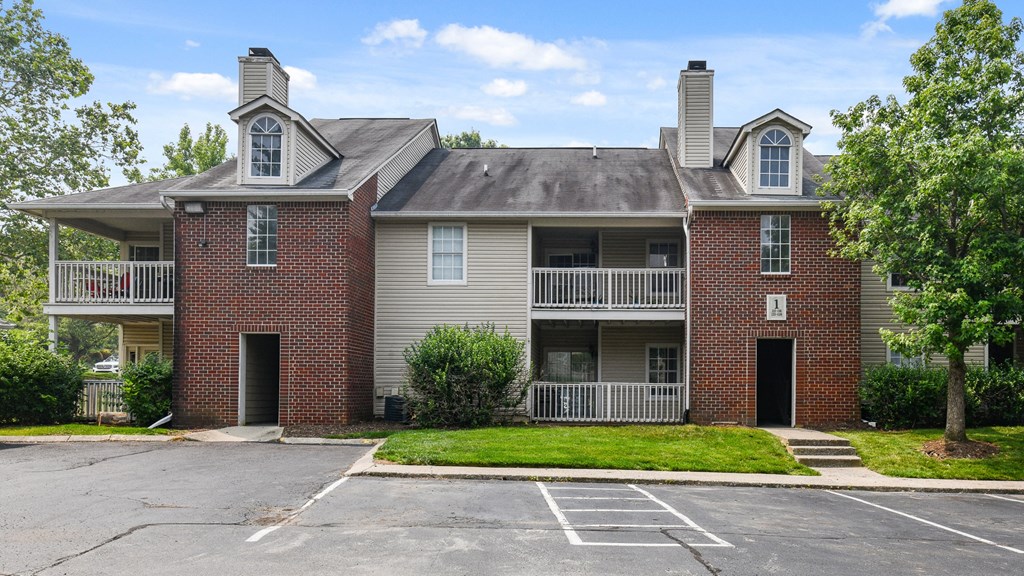 an apartment building with a parking lot and a lawn