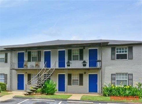 A grey apartment building with blue doors and windows.