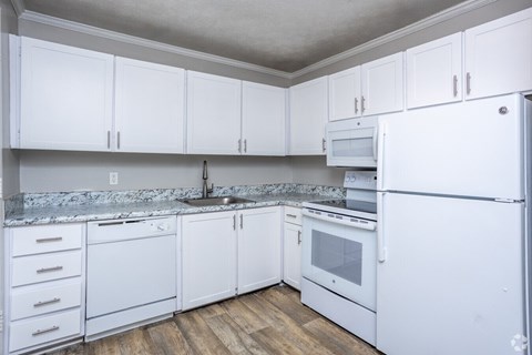 A kitchen with white cabinets and appliances.