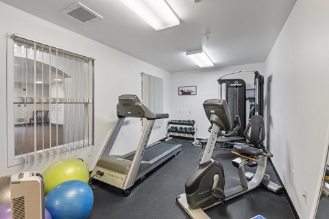 two treadmills and other exercise equipment in a gym with a window