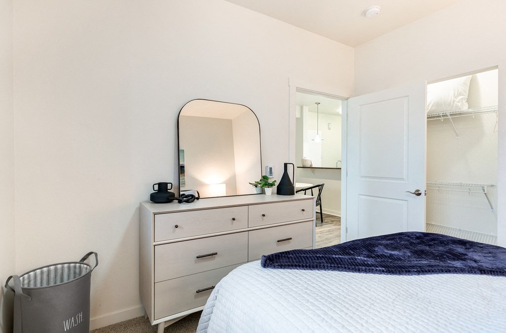 a bedroom with a bed and a dresser with a mirror