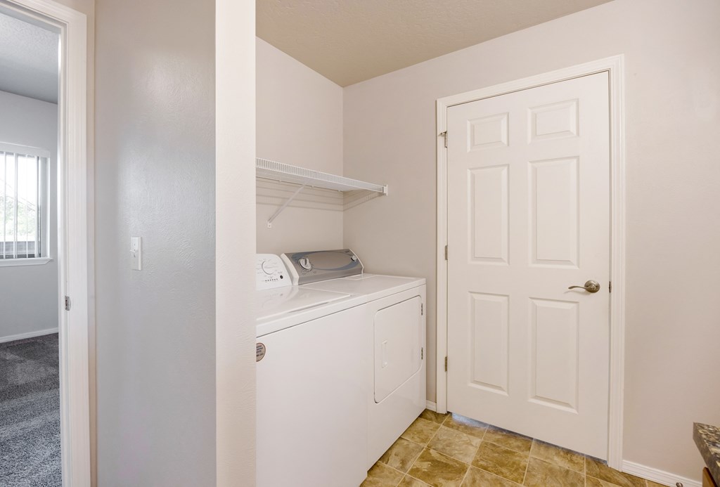 A white laundry machine sits in a small room with a door and a window. at Ashlyn Place, Missoula, MT, 59801