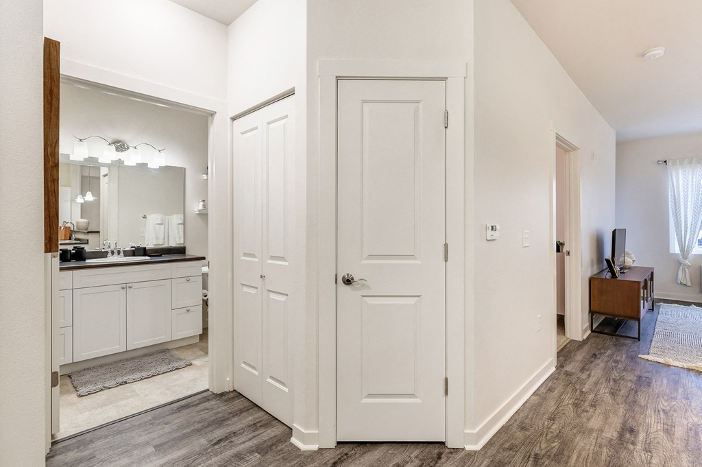 a bedroom with white doors and a bathroom with a sink and a mirror