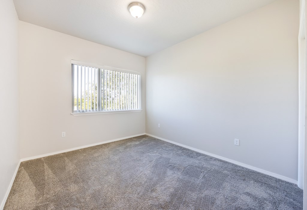 A room with a carpeted floor and a window with blinds. at Ashlyn Place, Missoula, Montana