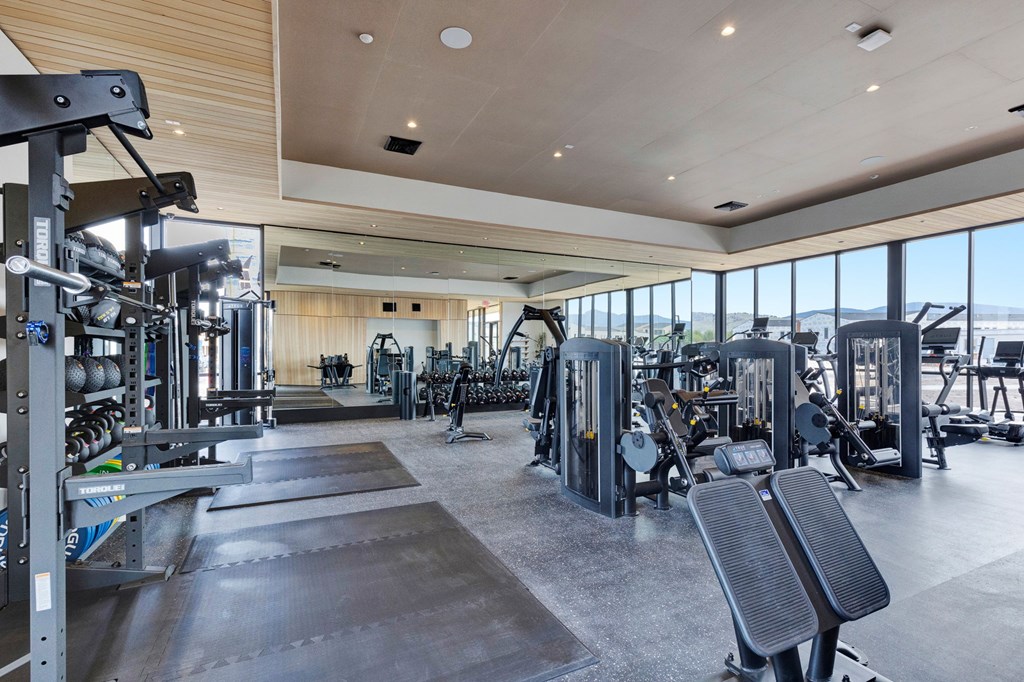 A spacious gym with a variety of equipment and a large window overlooking the beach.