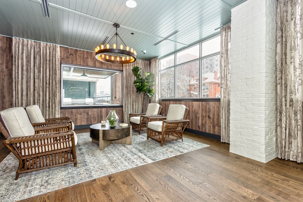 Resident common area with wooden furniture, modern style chandelier, and large windows at Sylvan Uptown, Colorado