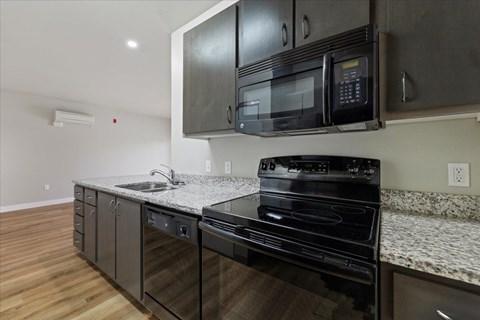 A black microwave is mounted above a black stove in a kitchen.