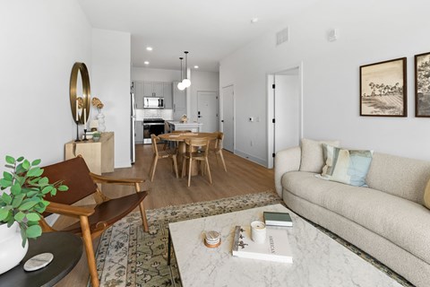 A living room with a couch, chair, and a table with a vase of flowers on it.