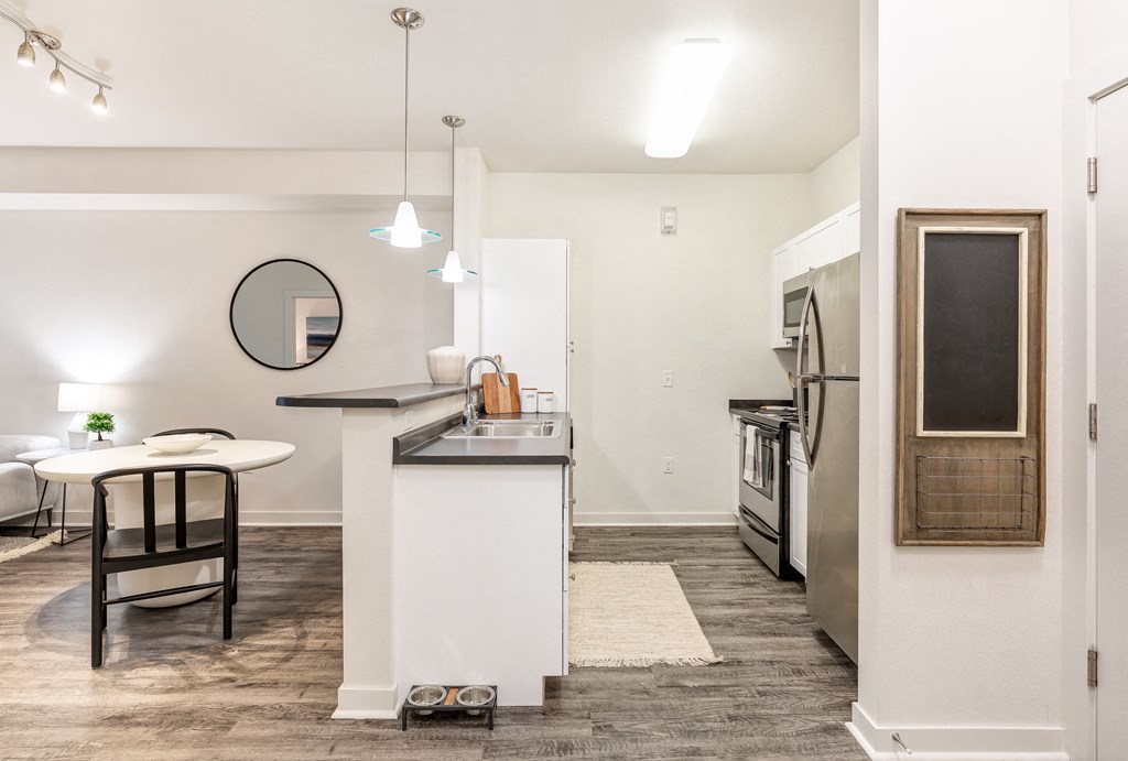 a living room with a kitchen and a dining area with a table and chairs at Corso Apartments, Missoula, MT