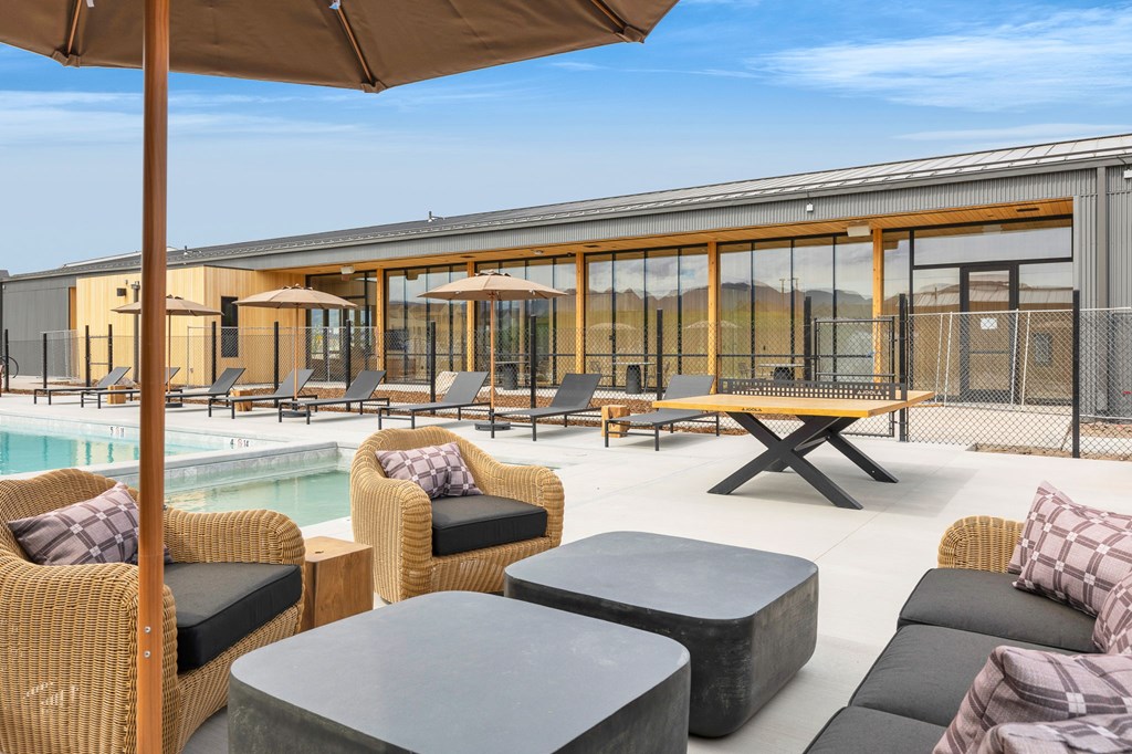 A patio area with wicker furniture and a pool.