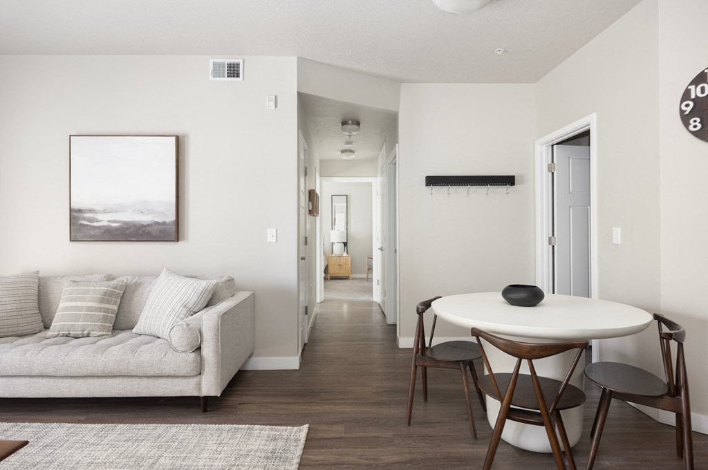 a small table and chairs in a living room with a couch and a hallway in the background
