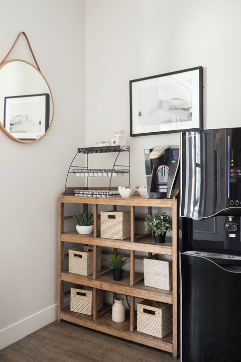 a shelf with baskets and plants next to a coffee machine in a living room at The Alloy at Geneva, Vineyard, UT, 84058