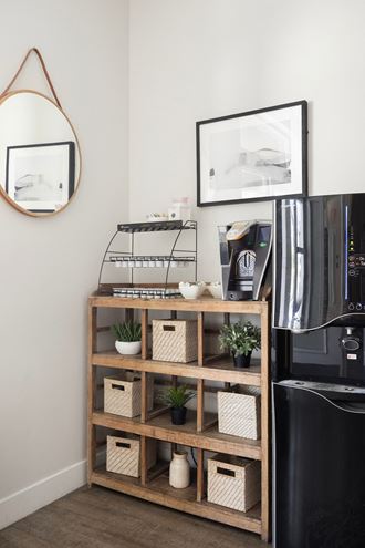 a shelf with baskets and plants next to a coffee machine in a living room