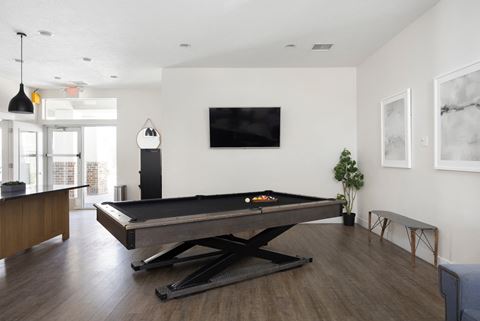 a living room with a pool table and a flat screen tv on the wall