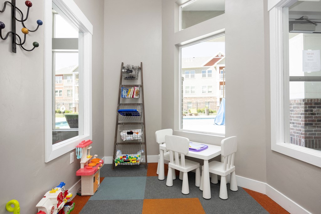 a play room with a table and chairs and a ladder with toys