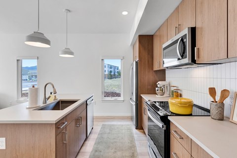A modern kitchen with wooden cabinets and a black stove top oven.